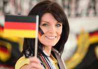 Woman-smiling-brightly-holding-up-german-flag.png
