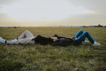 Male-friends-lying-down-on-grass-in-park-during-sunset-MASF22055.jpg